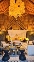 A cozy lounge area with a high ceiling, a central seating arrangement, and a decorative hanging light fixture.