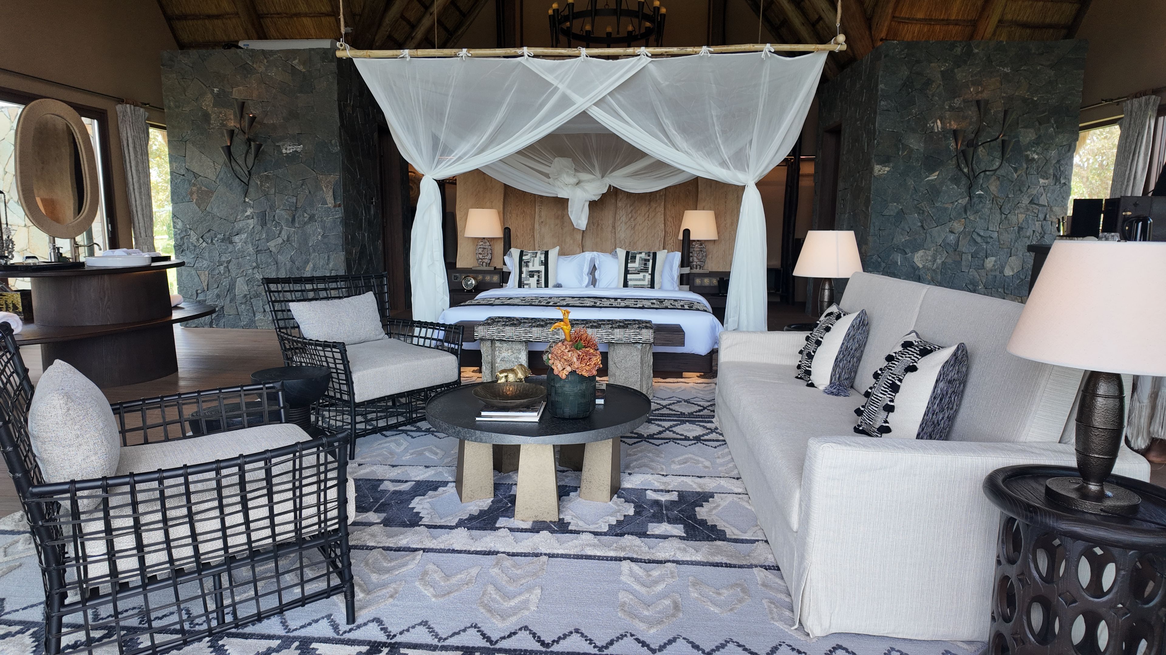Una habitación con una cama, un sofá, una silla, una mesa y una lámpara.