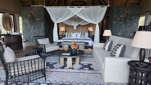 A room with a bed, a sofa, a chair, a table, and a lamp.
