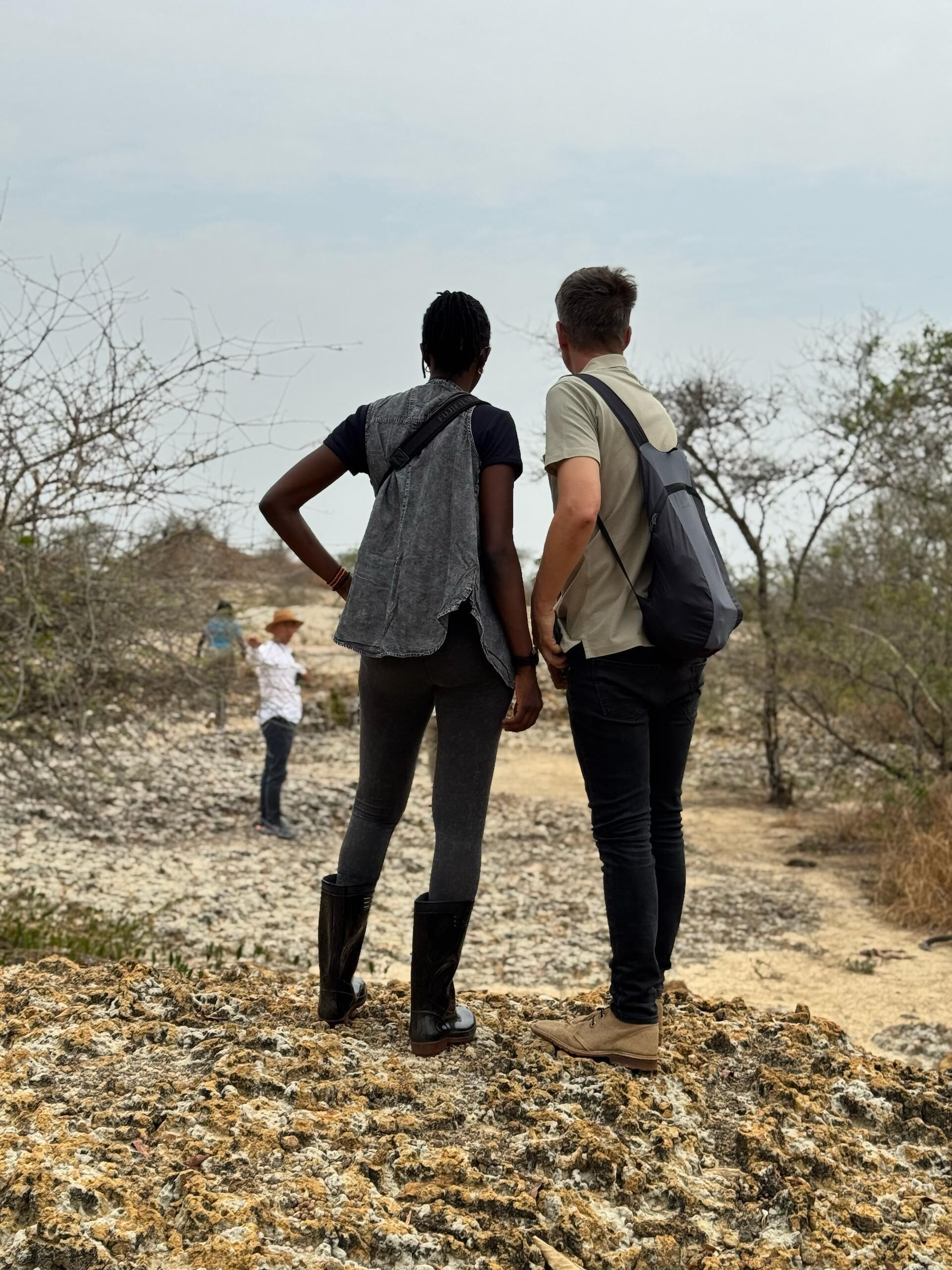 Two people walking on a rocky path with sparse vegetation.