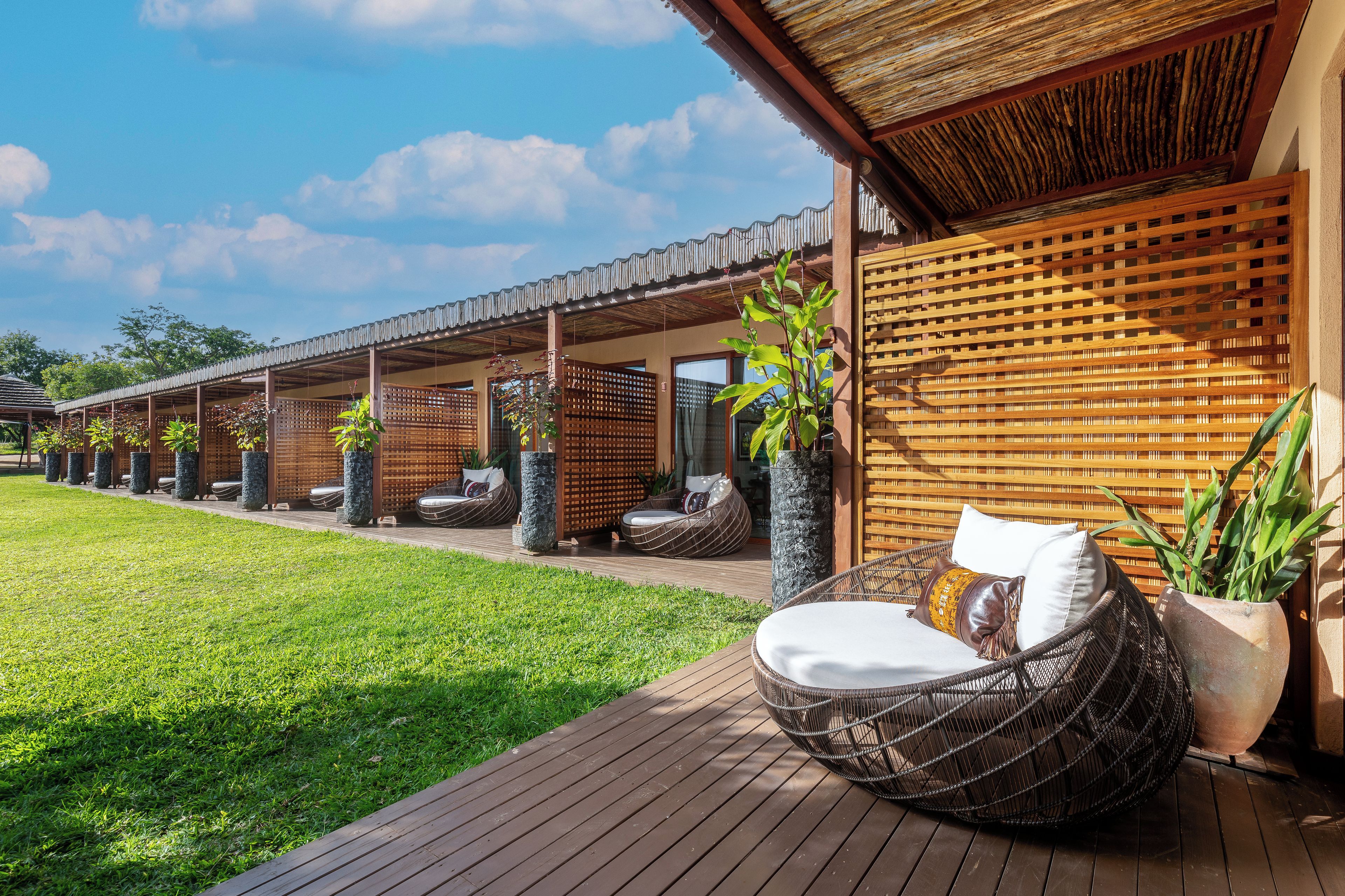 A series of outdoor seating areas with wicker furniture and planters, a wooden deck, and a covered walkway.