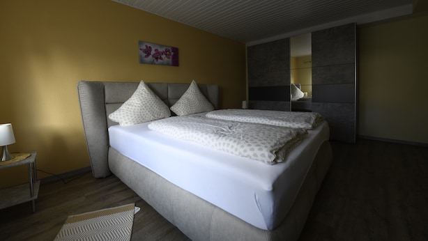 Un dormitorio moderno con una cama grande, una mesita de noche y una obra de arte colgada en la pared.