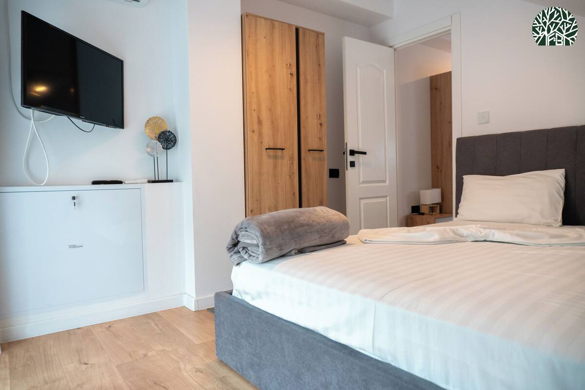 A bedroom with a bed, a TV mounted on the wall, and a wardrobe.