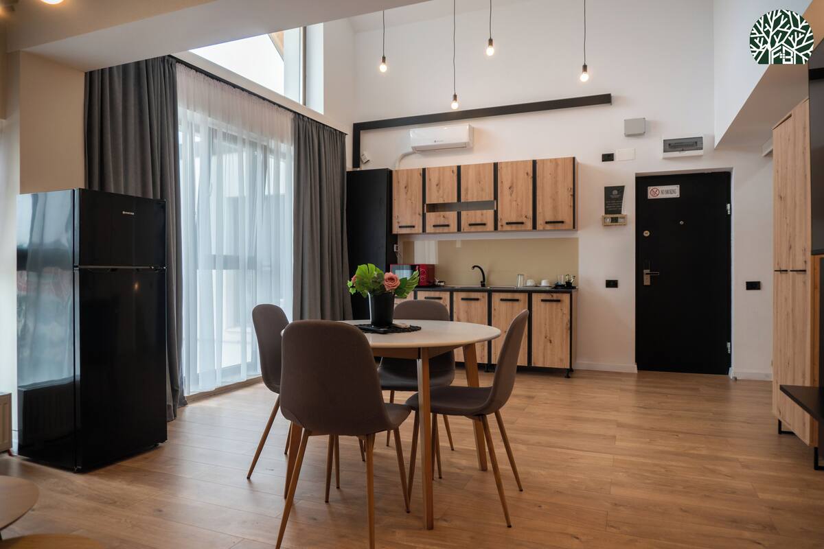 A modern kitchen with wooden cabinets, a black refrigerator, and a dining area with a round table and chairs.