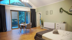 Une chambre d’hôtel moderne dotée d’un grand lit, d’un coin repas et offrant une vue à travers les portes vitrées.