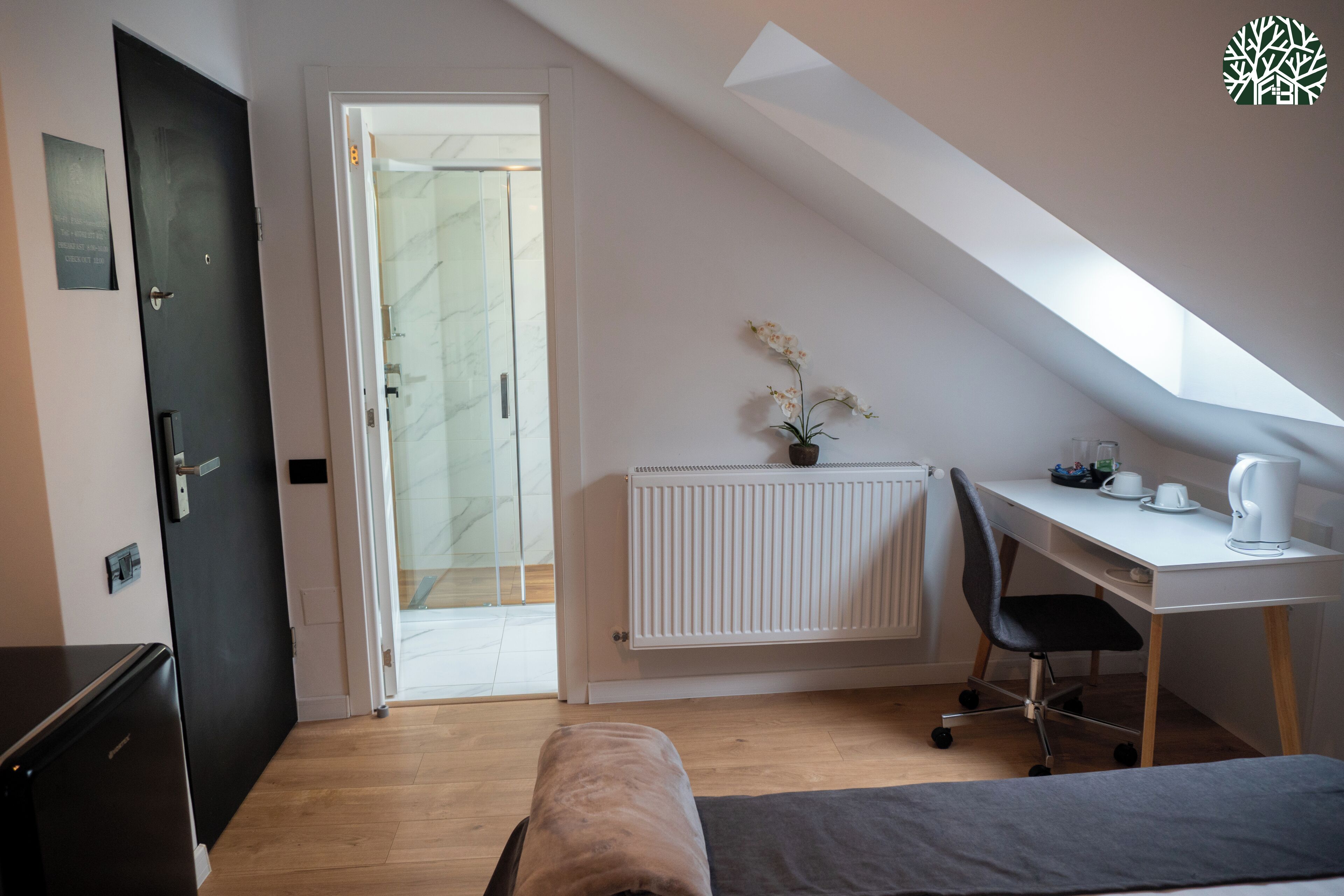 A small, modern room with a bed, a desk, and a radiator.