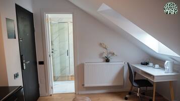 A small, modern room with a bed, a desk, and a radiator.