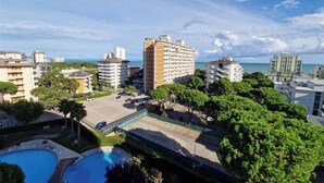 A high-rise hotel with multiple floors, a swimming pool, and surrounding greenery. - Stunning sea View From our Apartment With Terrace (Lignano Sabbiadoro)