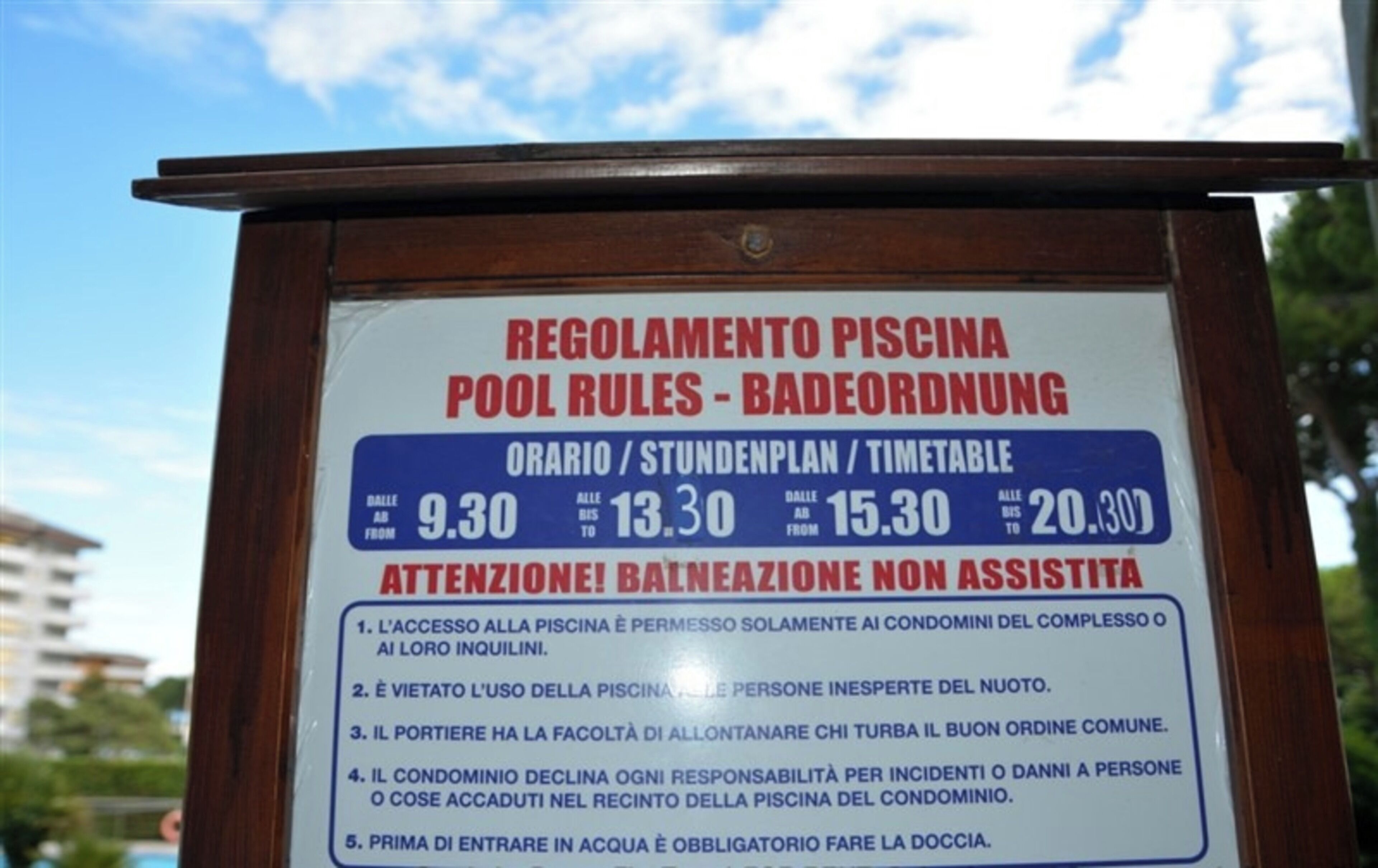 Placa com regras da piscina, horários de funcionamento e aviso sobre falta de assistência.