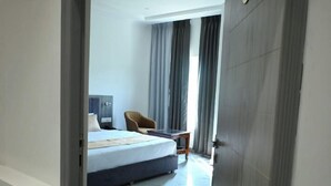 Ein Hotelzimmer mit einem Bett, einem Sessel, einem Schreibtisch und einem Deckenventilator.