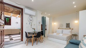 Ein kleines Hotelzimmer mit Bett, einem kleinen Tisch mit Stühlen, einer Sitzecke und einem Essbereich mit Blick nach außen.