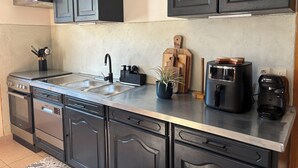 A modern kitchen with stainless steel appliances, black cabinetry, and a built-in oven.