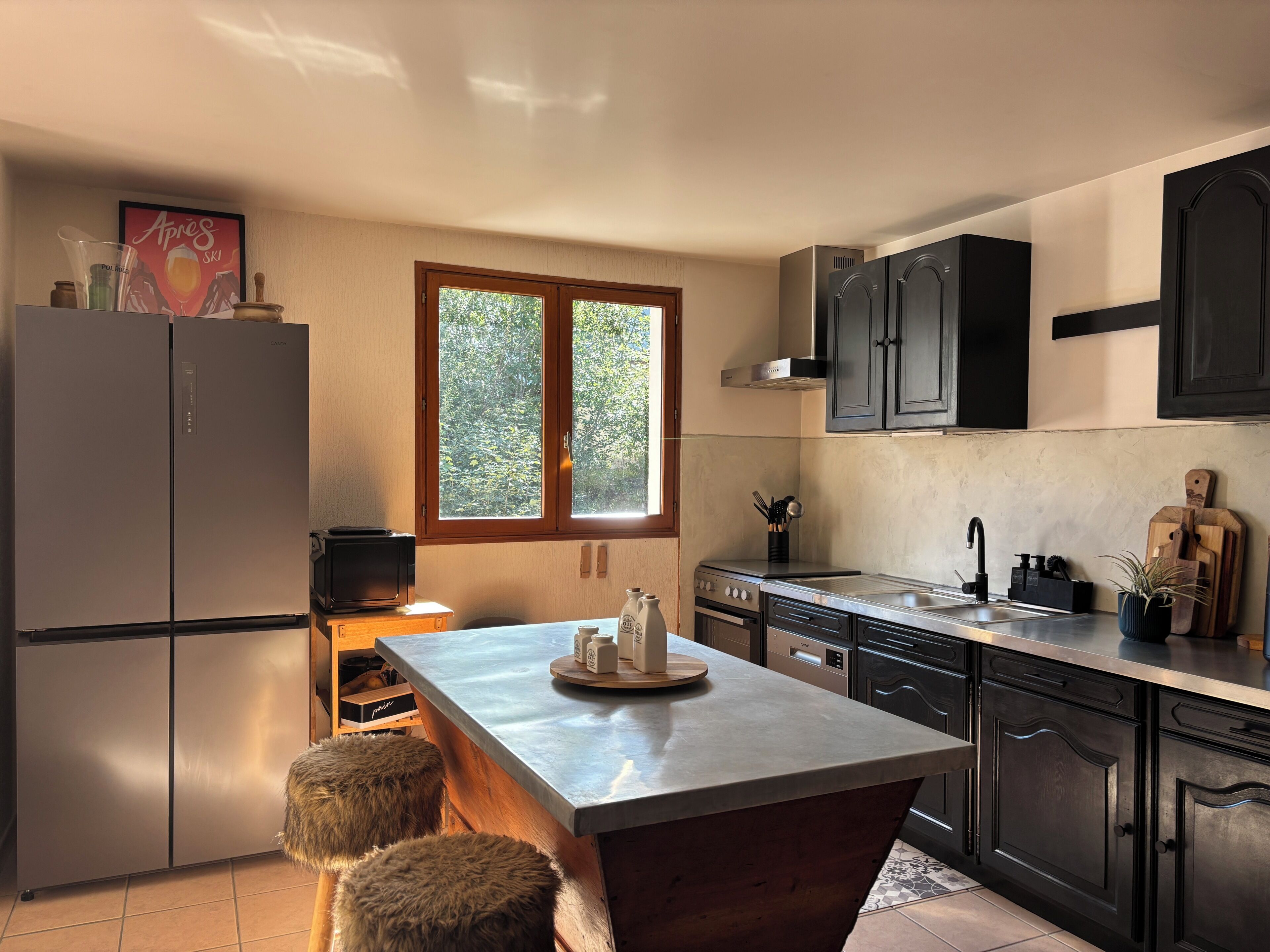 Una cocina moderna con una isla central, electrodomésticos de acero inoxidable y un ventanal que proporciona luz natural.