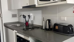 Eine kleine Küche mit weißen Schränken, einer Mikrowelle, einem Toaster und einem Geschirrspüler.