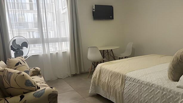 Ein Hotelzimmer mit einem Bett, einem Schreibtisch, einem Stuhl und einem Ventilator.