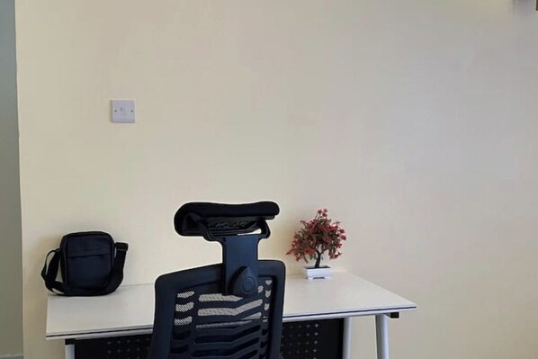 A small office space with a white desk, a black office chair, a black bag, and a potted plant. - Airport view Utawala 2 bdr (near JKIA)@0703500856 (Nairobi County)