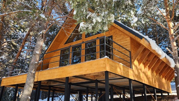 A wooden cabin with a sloped roof, large windows, and a wooden deck. - Aparan park (Yeghipatrush)