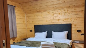 A wooden-paneled room with a bed, a nightstand, and a window with a view. - Aparan park (Yeghipatrush)