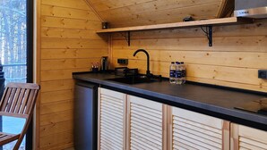 A modern kitchen with wooden paneling, a black countertop, a stainless steel sink, and a built-in oven. - Aparan park (Yeghipatrush)