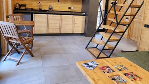 A modern kitchen with wooden cabinetry, a dining area with a table and chairs, and a staircase leading to an upper level. - Aparan park (Yeghipatrush)