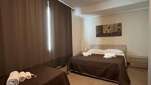 Une chambre d’hôtel avec deux lits, un tableau au mur et un luminaire au plafond.