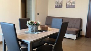 Un coin repas comprenant une table en bois, quatre chaises, un vase avec des fleurs et un canapé.