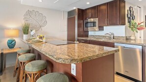 A modern kitchen with granite countertops, stainless steel appliances, and wooden cabinets. - Top Notch Rental Experience Awaits! (Lahaina)