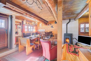 A rustic cabin interior with a dining area, a fireplace, and a television.