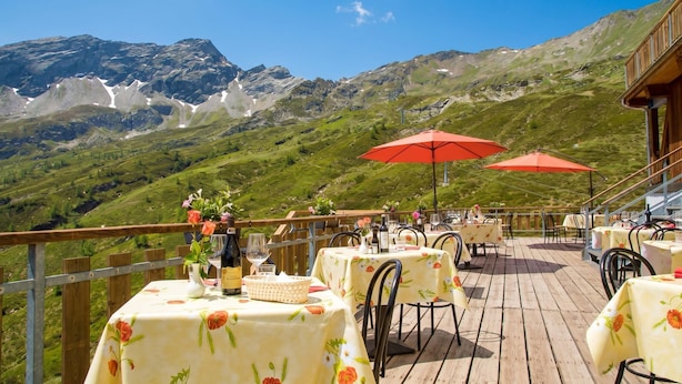 A terrace with tables and chairs, a wooden deck, and a mountainous backdrop. - Rustico Al Museo Bosco Gurin for 6 (Bosco Gurin)