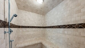 Une douche d’angle avec des carreaux de couleur beige et une bordure décorative.