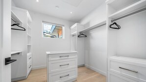 A modern walk-in closet with white cabinetry, multiple drawers, and hanging space.