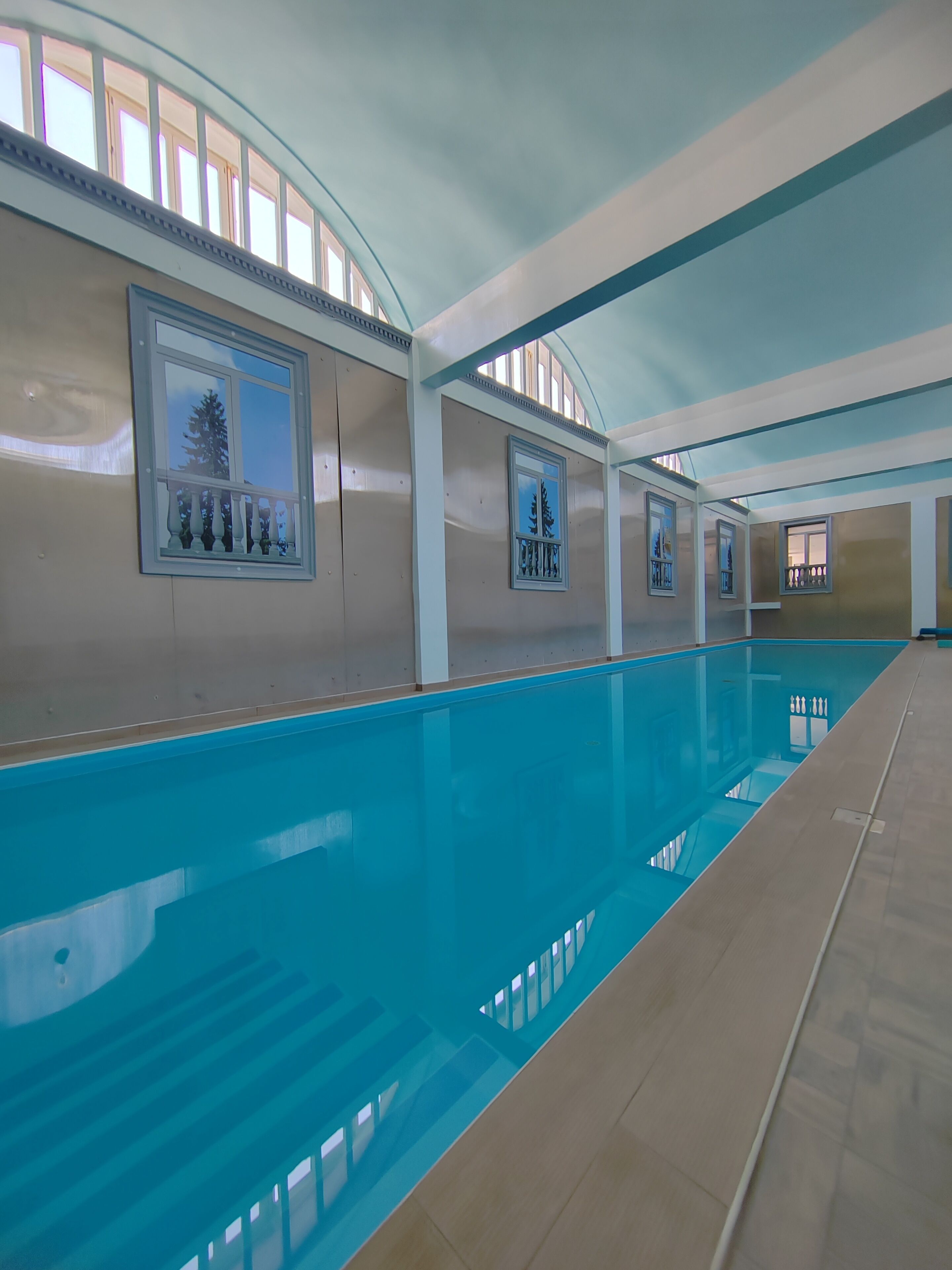 A swimming pool with a tiled floor, framed pictures on the walls, and a curved ceiling.