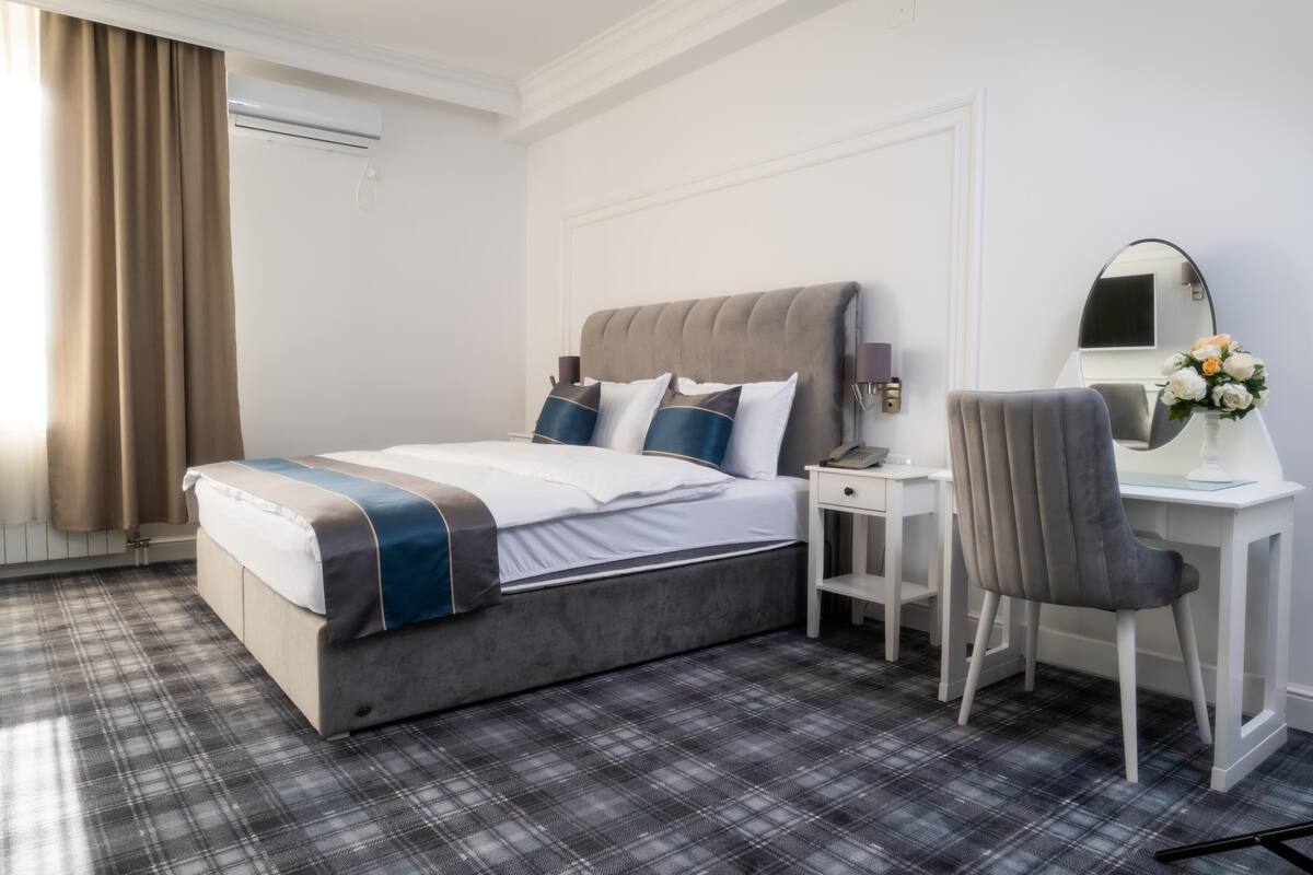 Une chambre d’hôtel avec un lit, un bureau, une chaise et un miroir.
