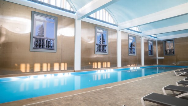 An indoor swimming pool with wooden flooring and lounge chairs. - Mio City Hotel (Kula)