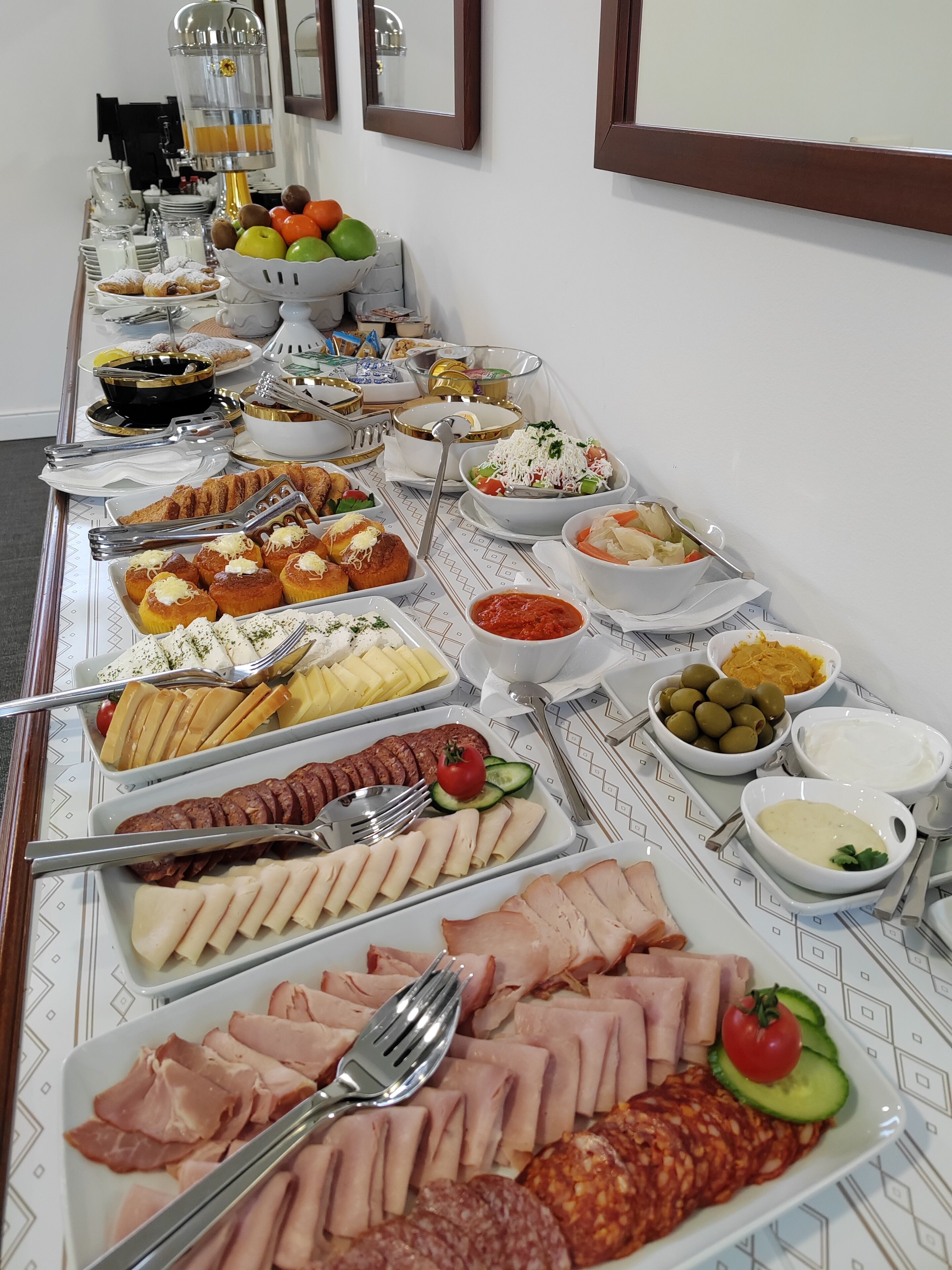 A buffet table with various food items including meats, cheeses, and salads.