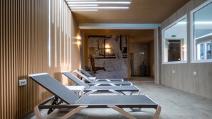 A modern waiting area with wooden paneling, a stone wall, and a view of an outdoor area. - Mio City Hotel (Kula)