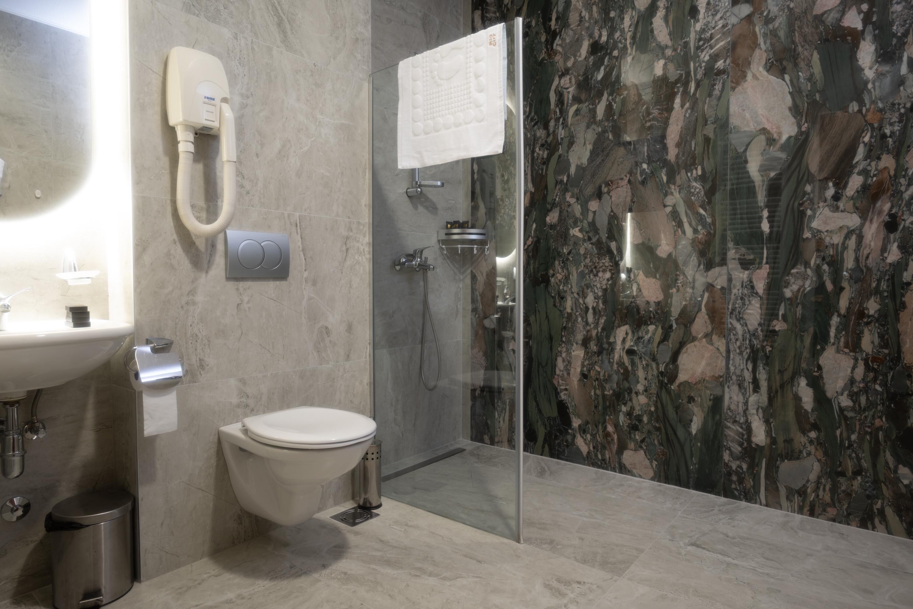 A modern bathroom with a toilet, sink, and glass-enclosed shower.