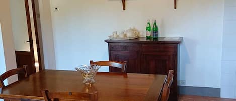 Un coin repas avec une table et des chaises en bois, un luminaire suspendu et un tableau au mur.