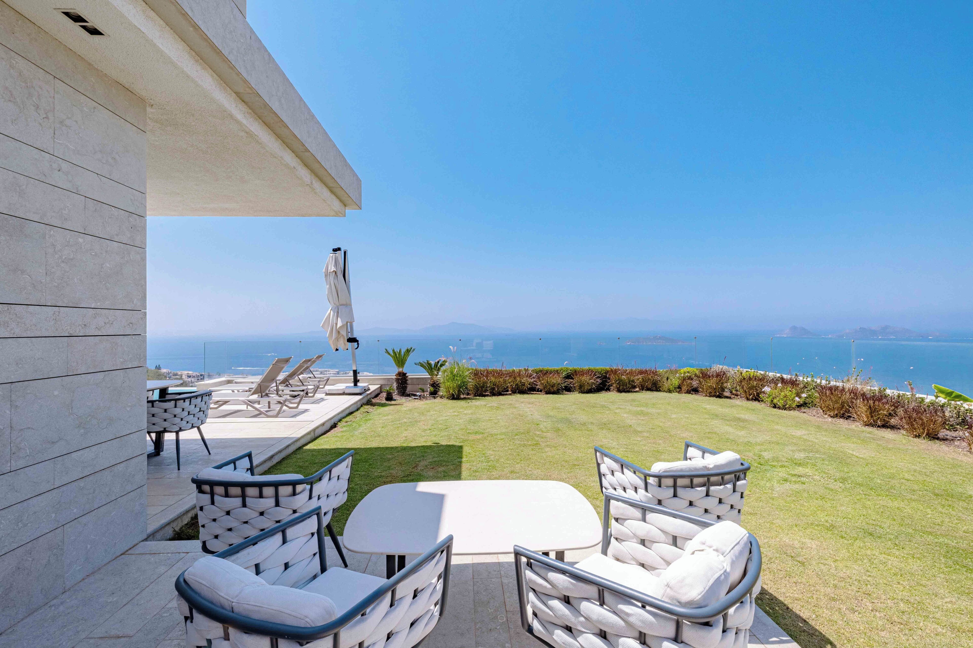 Une terrasse avec des meubles d’extérieur, une table et une vue sur l’océan.