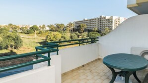 A balcony with a green table and a white wall.