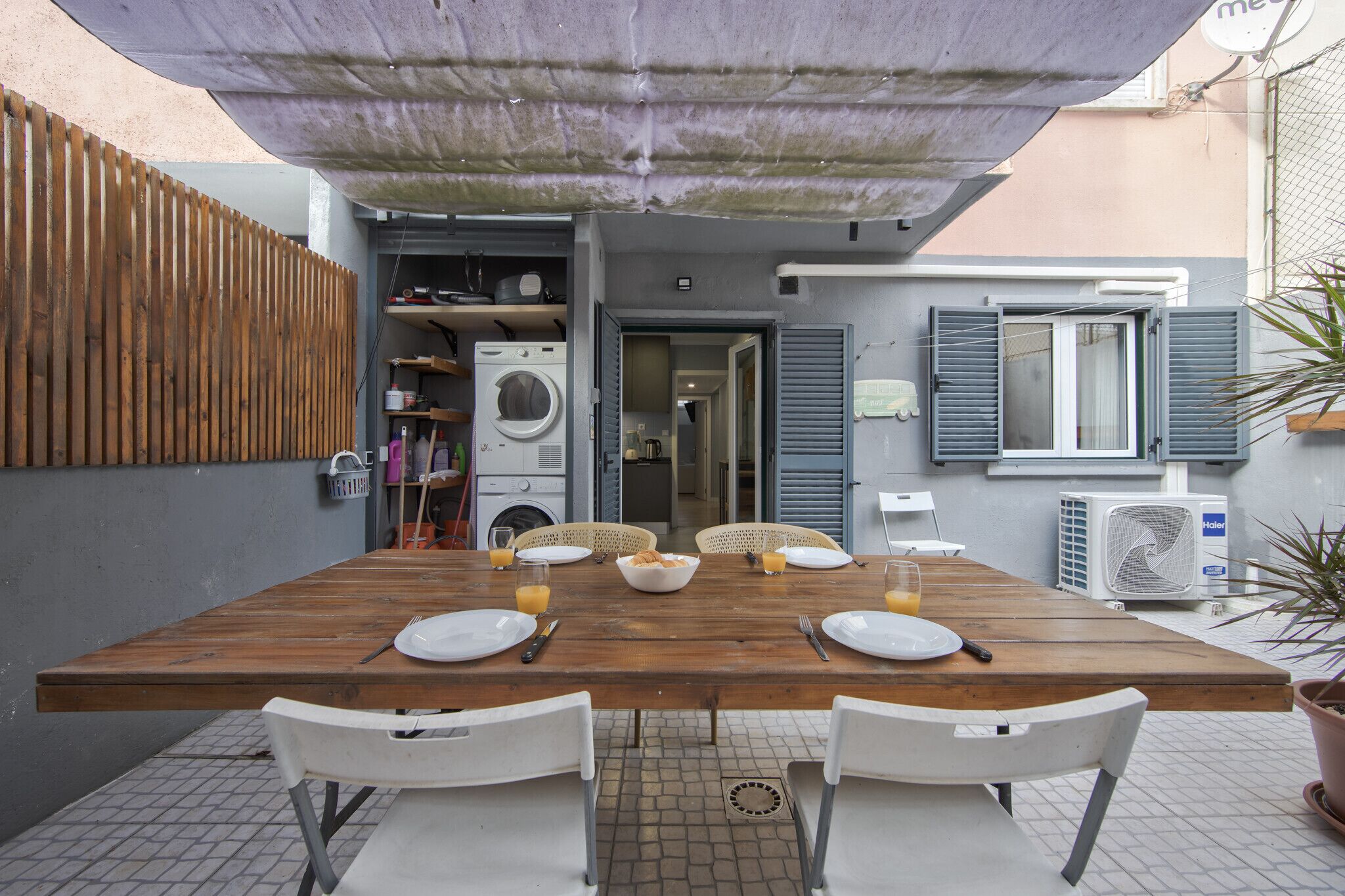 Un comedor con una mesa de madera, sillas blancas y un ventilador de techo.