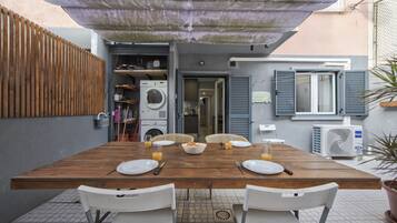 Un comedor con una mesa de madera, sillas blancas y un ventilador de techo.