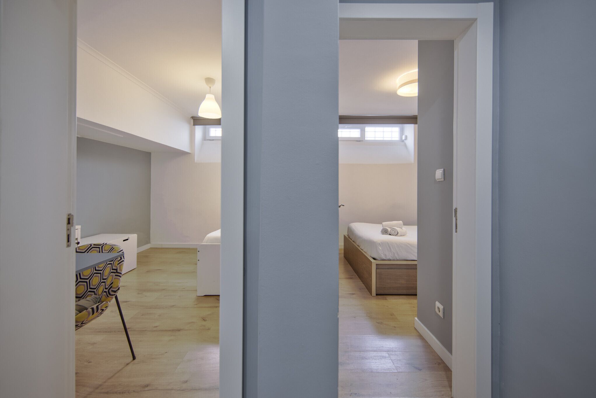 Un pasillo estrecho que conduce a un dormitorio con cama y mesita de noche.