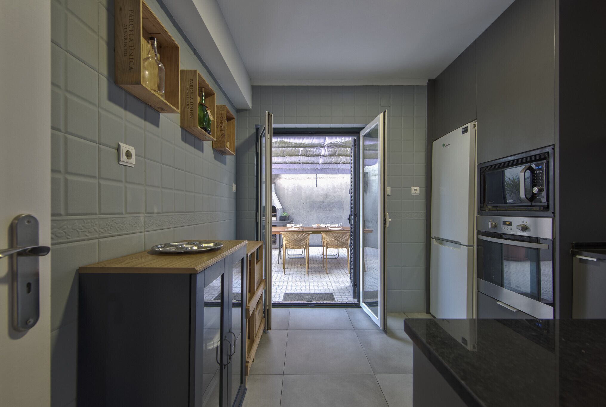 A kitchen with a refrigerator, oven, and a dining area with a table and chairs.