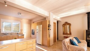 Une cuisine moderne avec des meubles en bois, un four encastré et un réfrigérateur. Une grande fenêtre offre une vue sur l’extérieur.