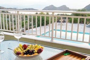 Un balcón con vista a la piscina, un cuenco de fruta y dos vasos de agua.