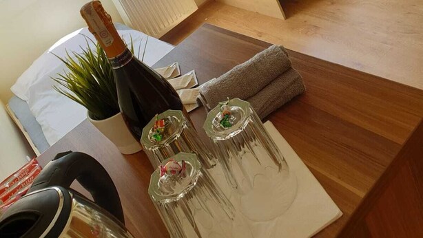 A compact room with a bed, a radiator, and a table with a bottle and glasses. - Rentumi Hostel Świnoujście Noclegi (Swinoujscie)