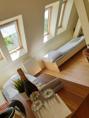 A compact room with a bed, a radiator, and a table with a bottle and glasses. - Rentumi Hostel Świnoujście Noclegi (Swinoujscie)