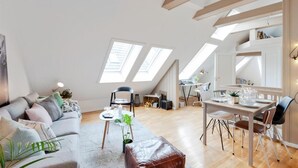 A spacious loft apartment with high ceilings, skylights, a dining area, and a cozy seating area. - Urban Apartment - City Center (Bergen)