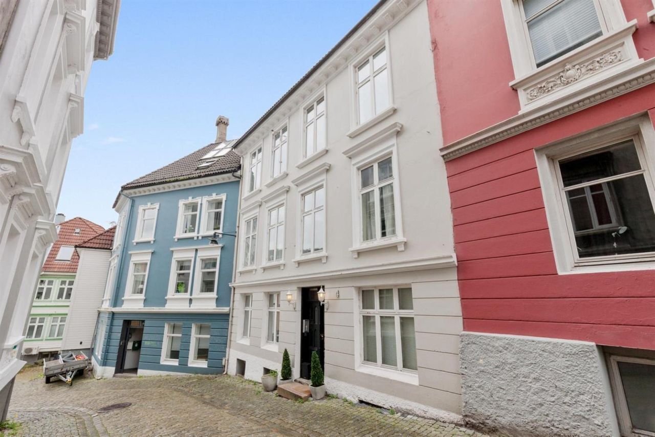 A narrow street with colorful buildings, cobblestone pavement, and a visible entrance to a building with a black door.